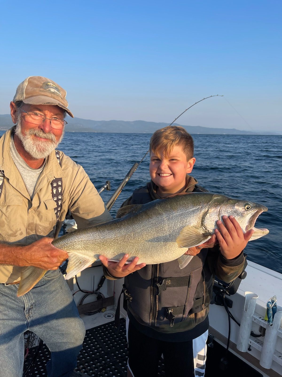 A man and a boy are holding a large fish on a boat.