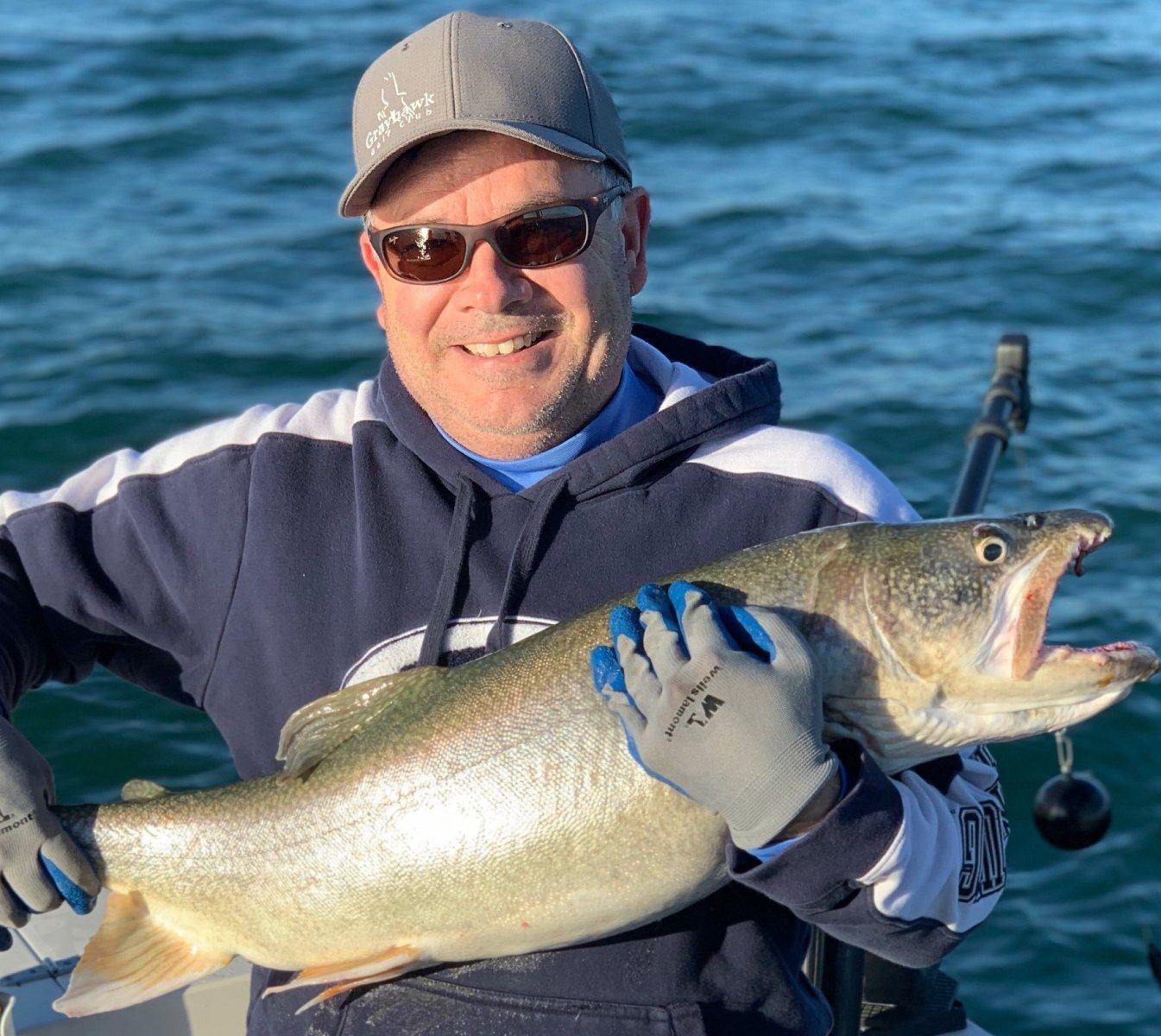 A man is holding a large fish with his mouth open