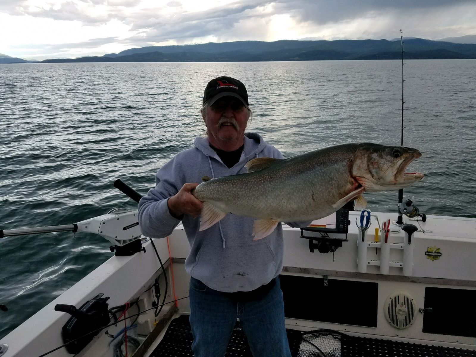 A man is holding a large fish on a boat in the water.