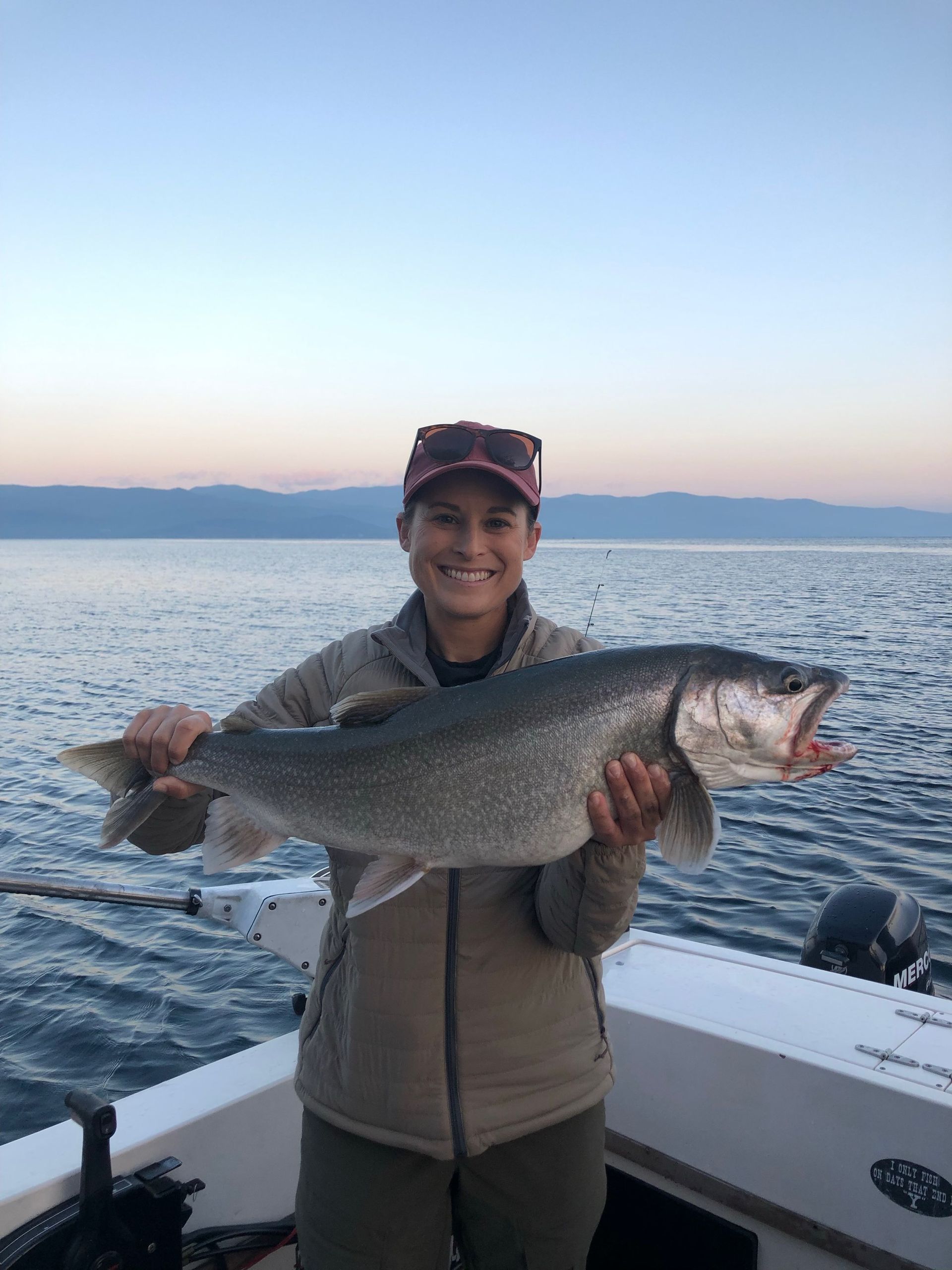 A woman is holding a large fish on a boat.