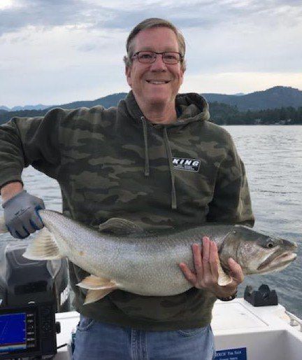 A man is holding a large fish on a boat