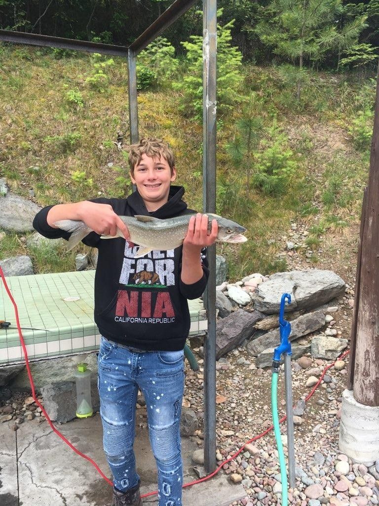 A young boy is holding a large fish in his hands.