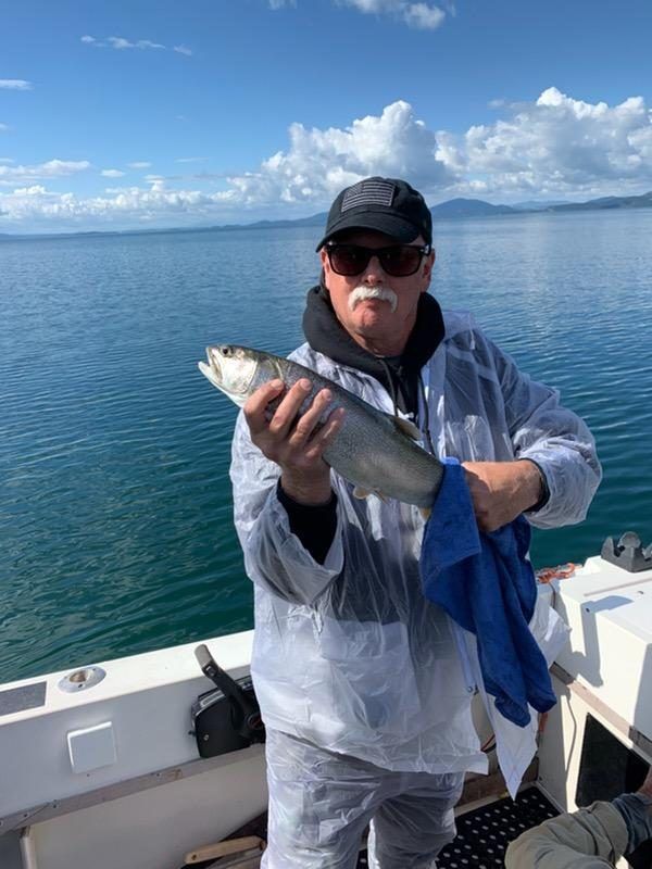 A man is holding a fish on a boat in the water.