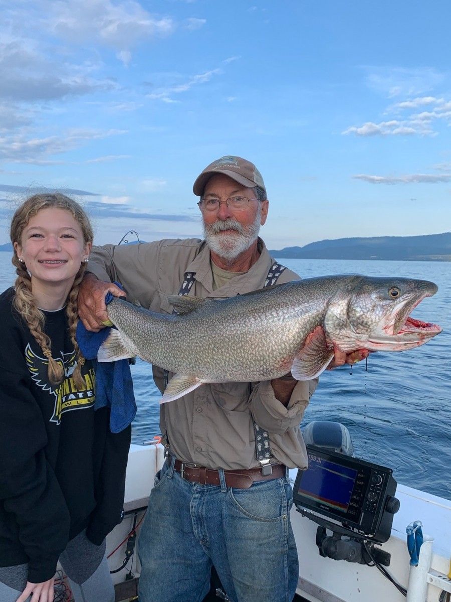 A man and a girl are holding a large fish on a boat.