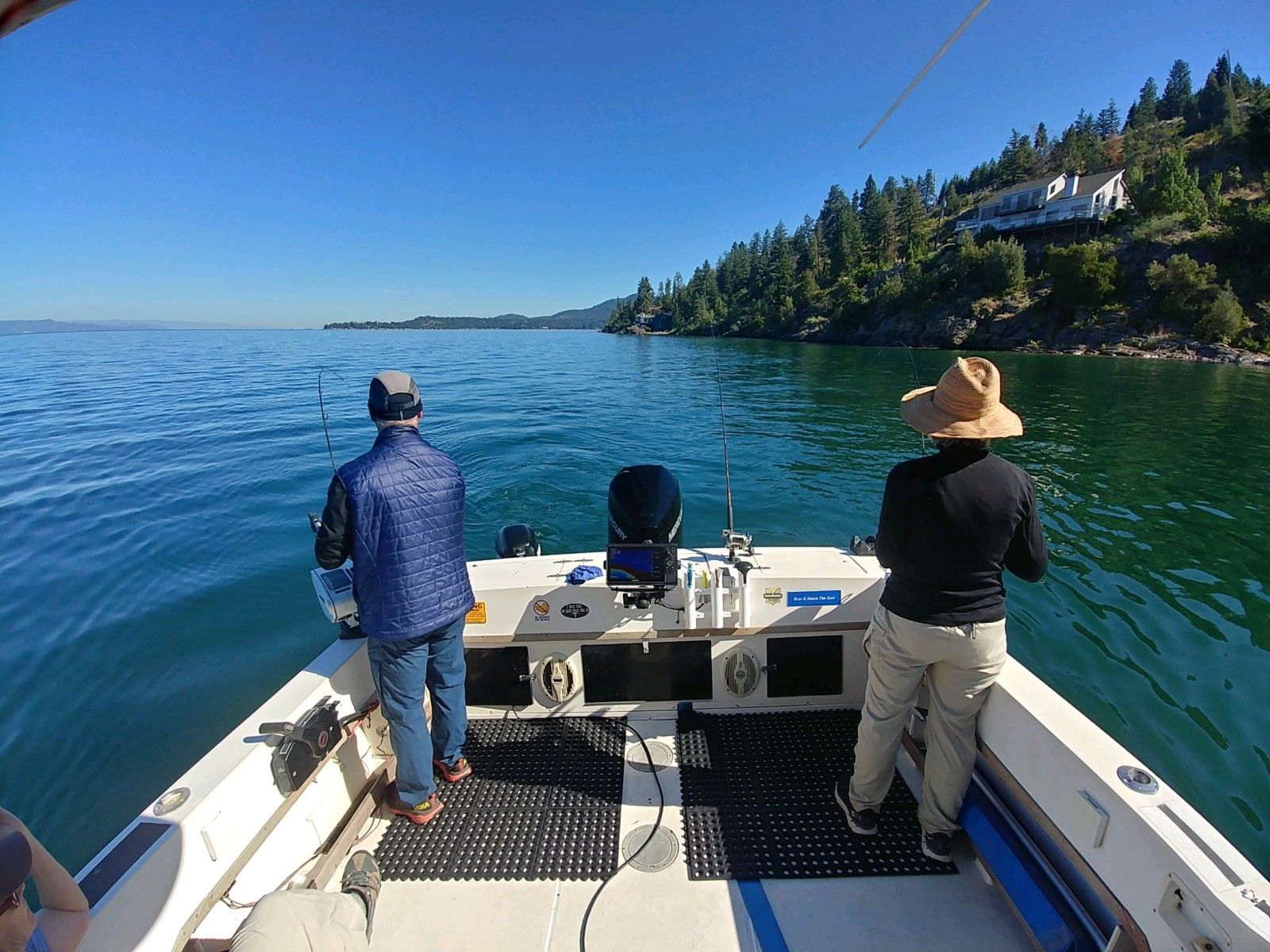 Two men are fishing on a boat in the water.