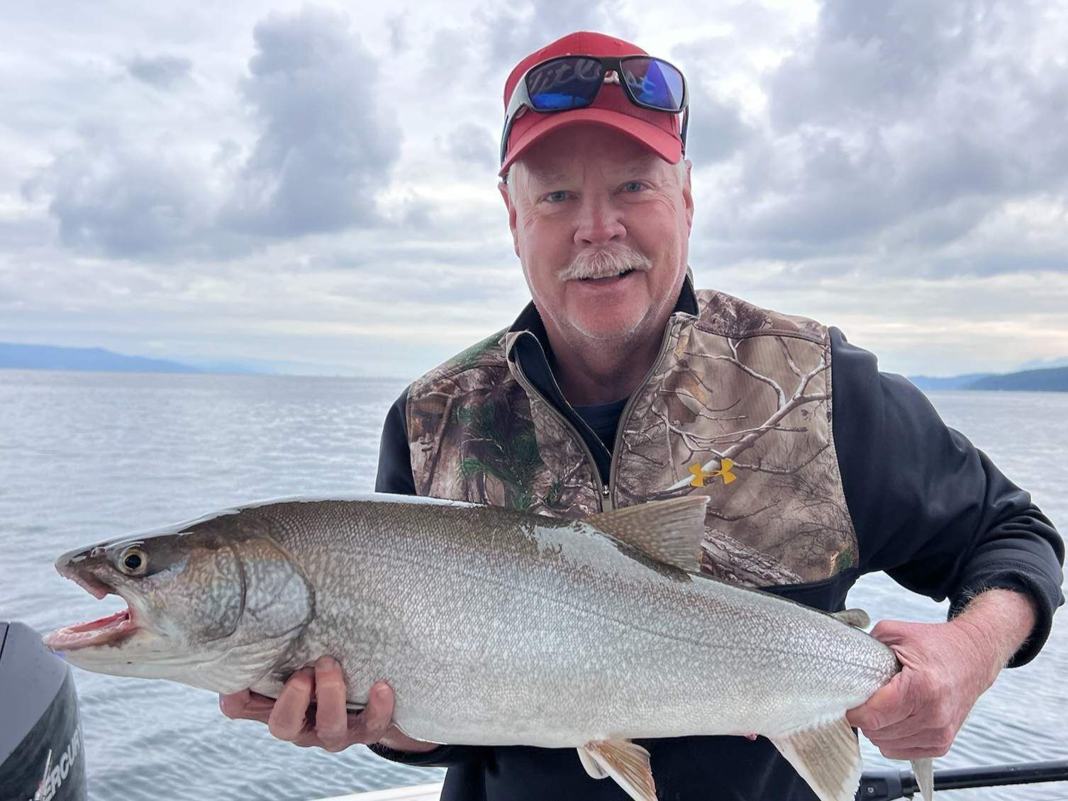 A man is holding a large fish in his hands on a boat.
