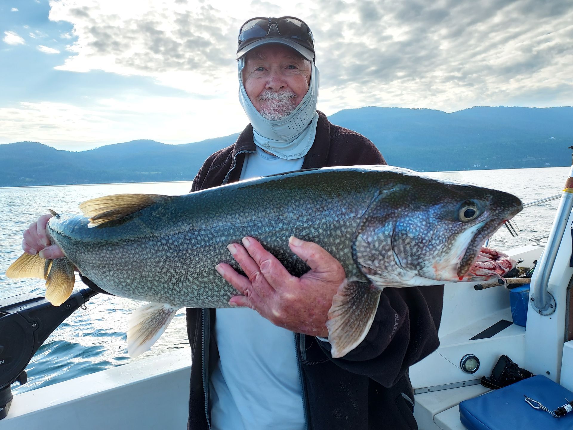 A man is holding a large fish on a boat.