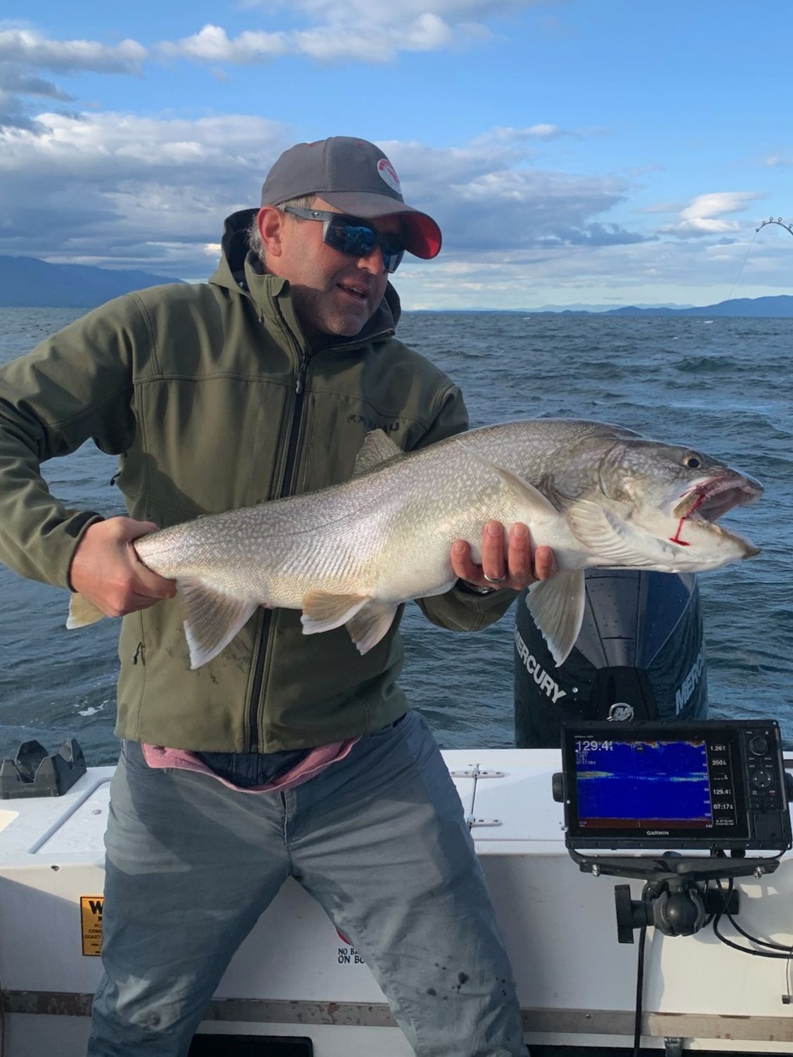 A man is holding a large fish on a boat.