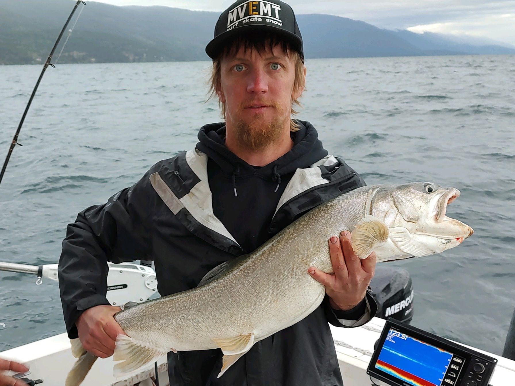 A man is holding a large fish on a boat.