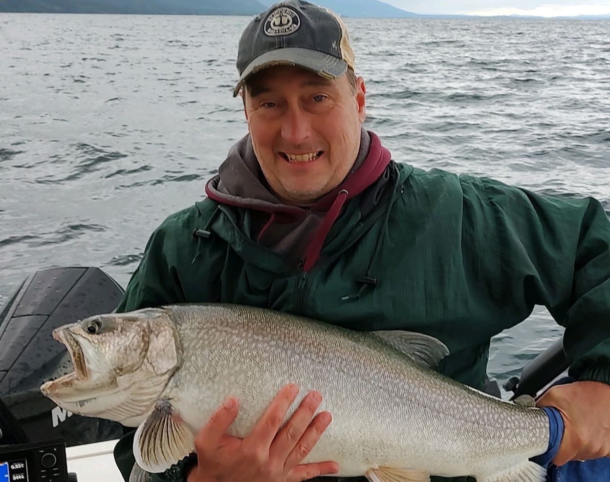 A man is holding a large fish on a boat.