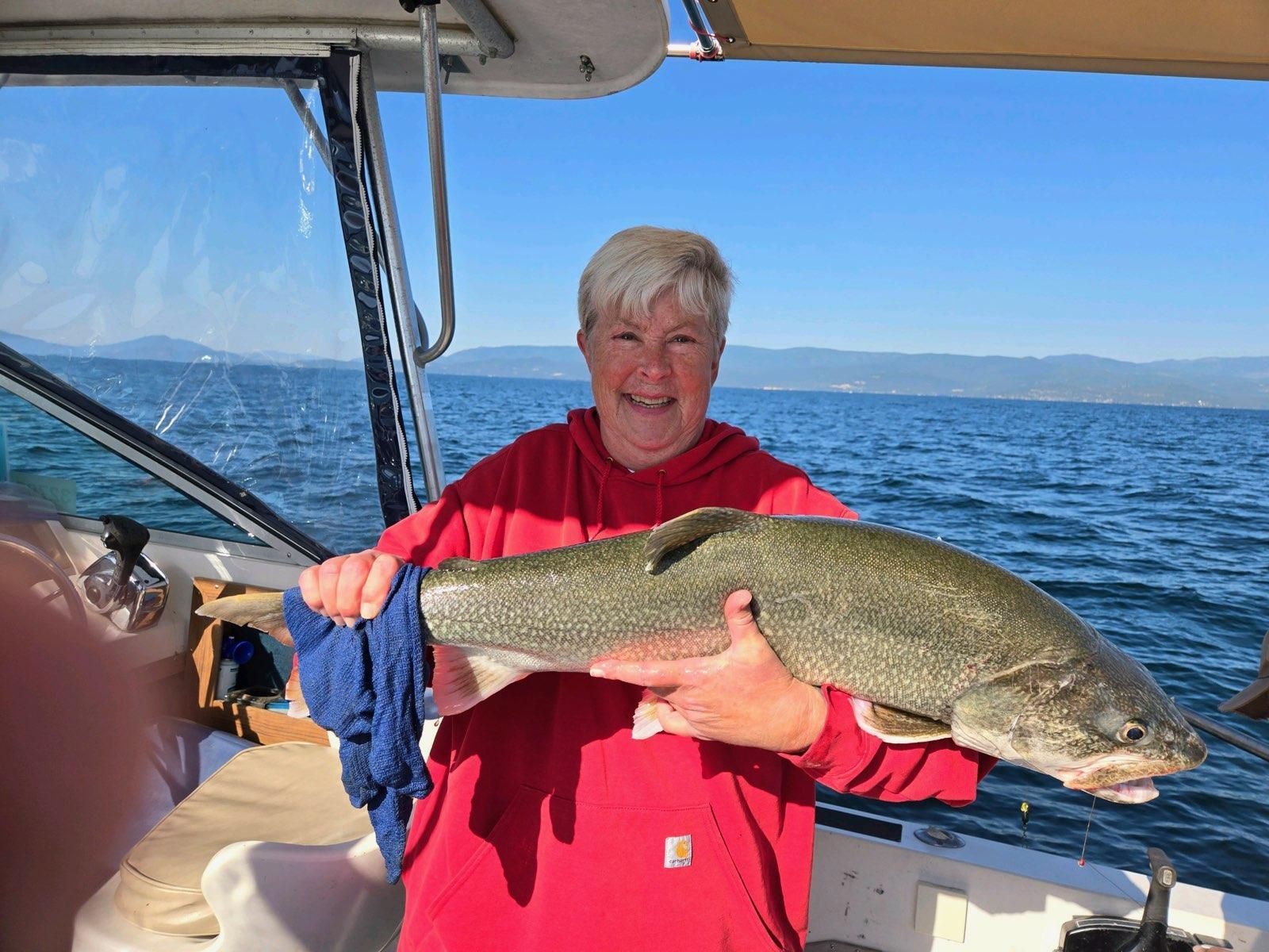 A woman is holding a large fish on a boat.