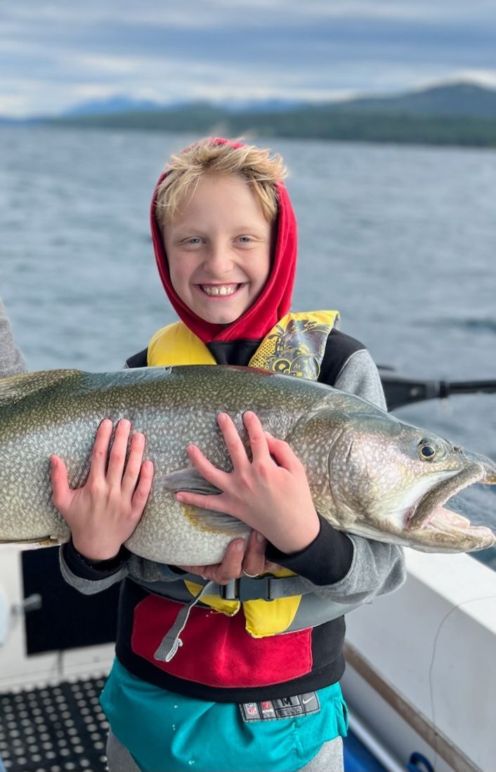 A young boy is holding a large fish on a boat.