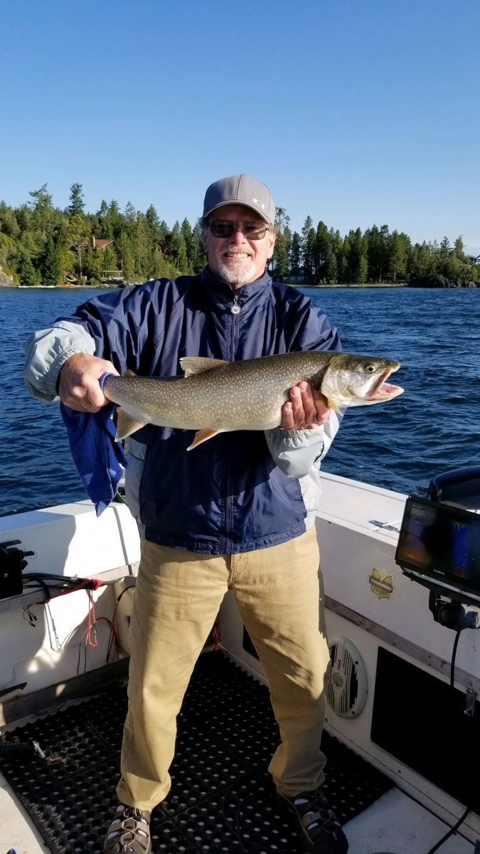 A man is standing on a boat holding a large fish.
