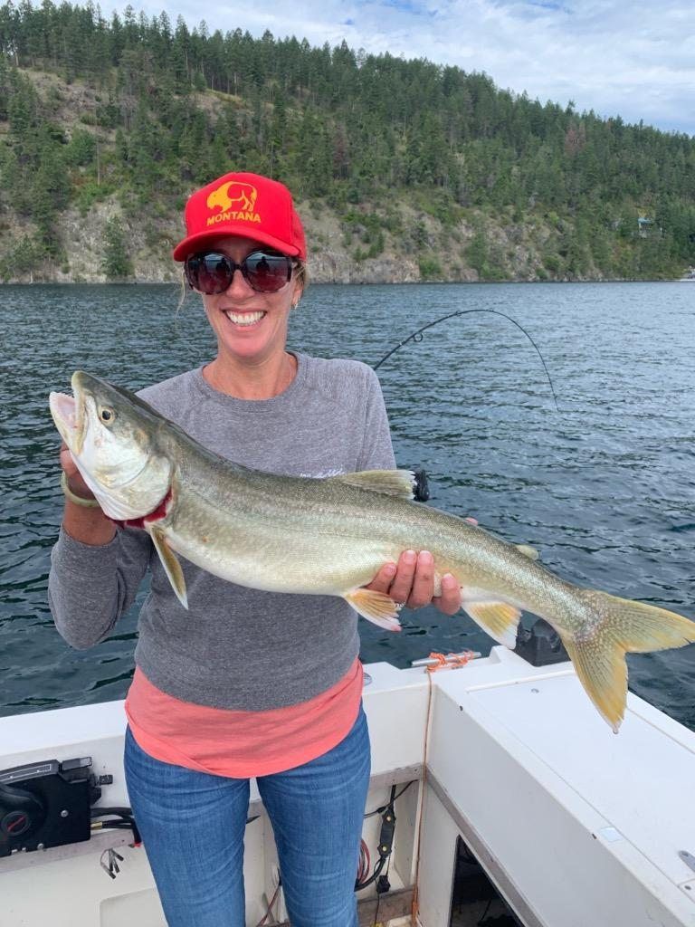 A woman is holding a large fish on a boat.