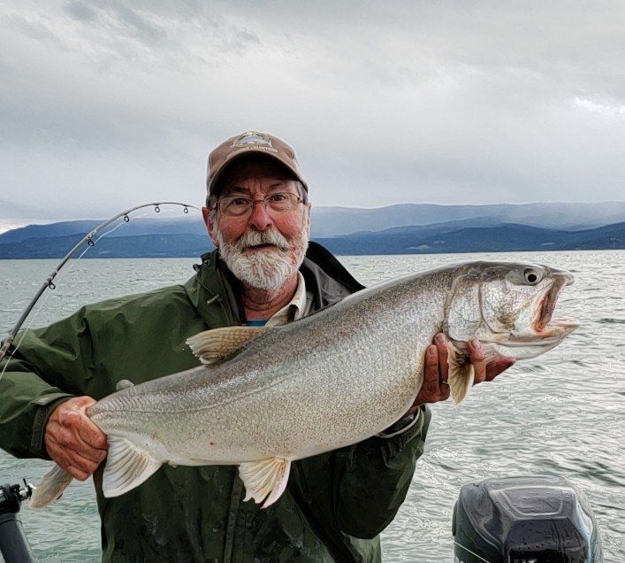 A man is holding a large fish in his hands on a boat.