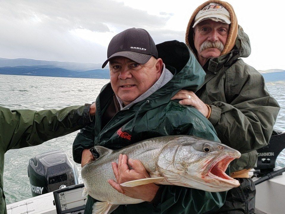 Two men are holding a large fish on a boat.