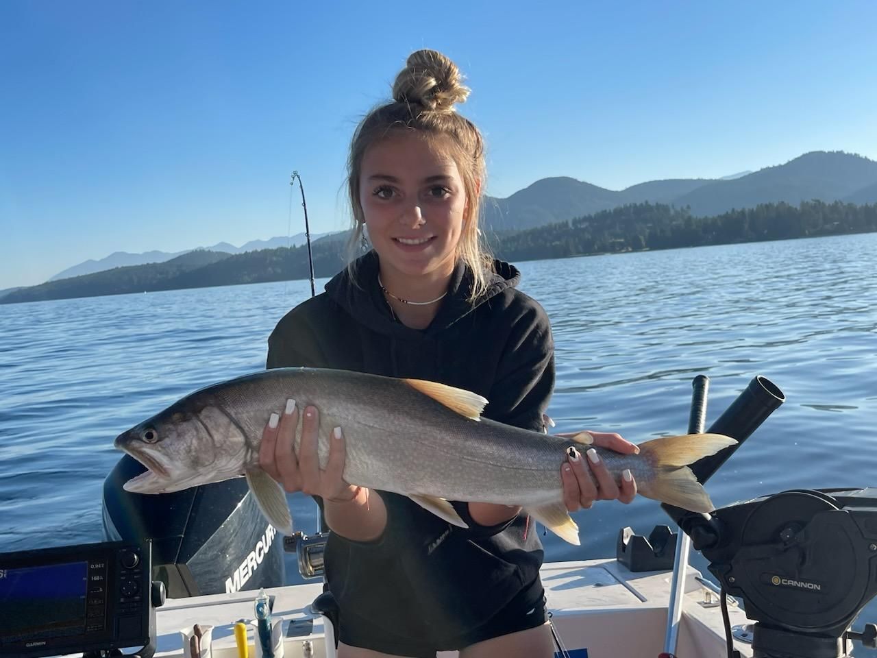 A woman is holding a fish on a boat in the water.