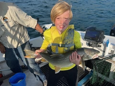 A young boy is holding a large fish on a boat.