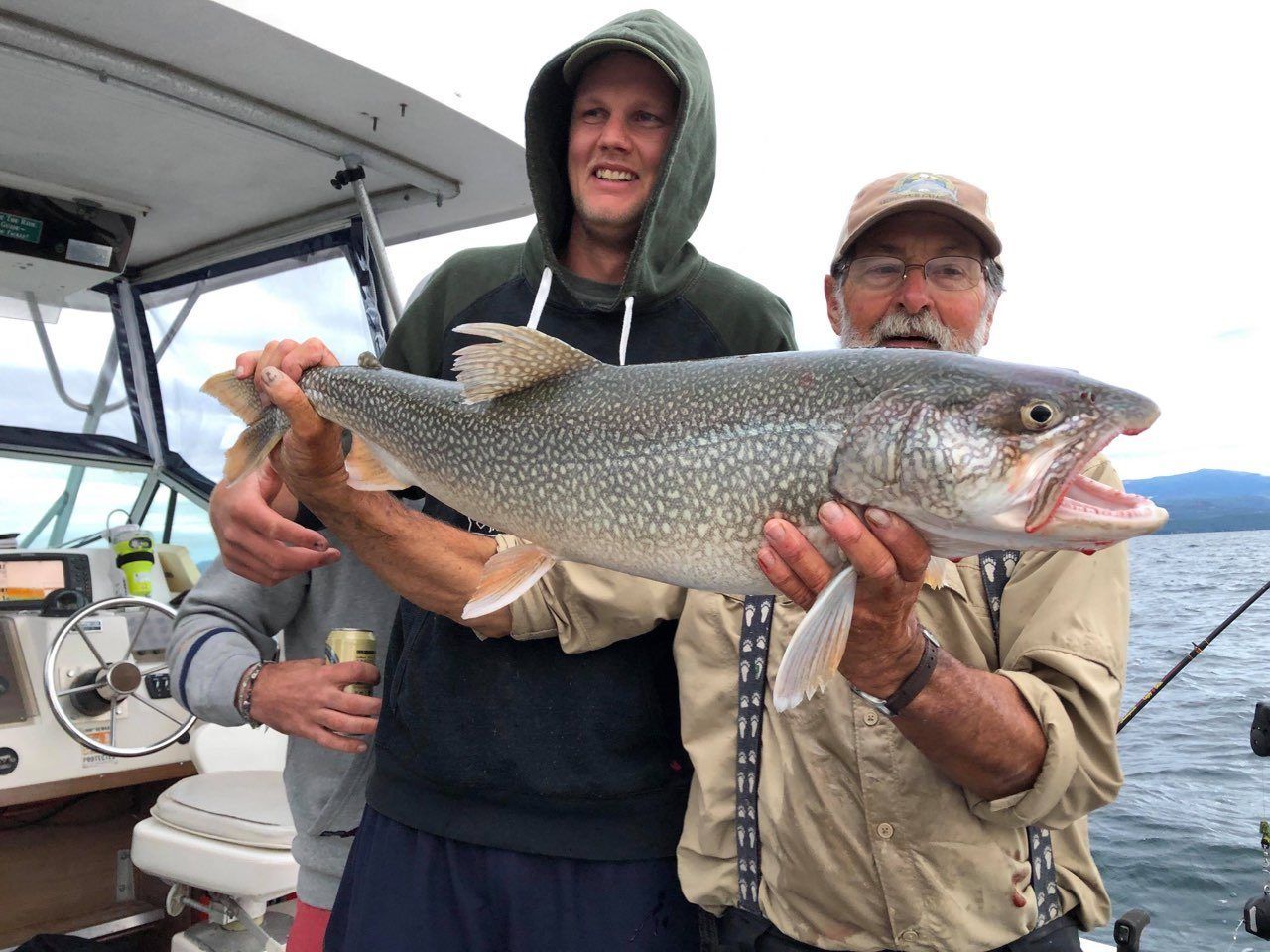 Two men are holding a large fish on a boat.