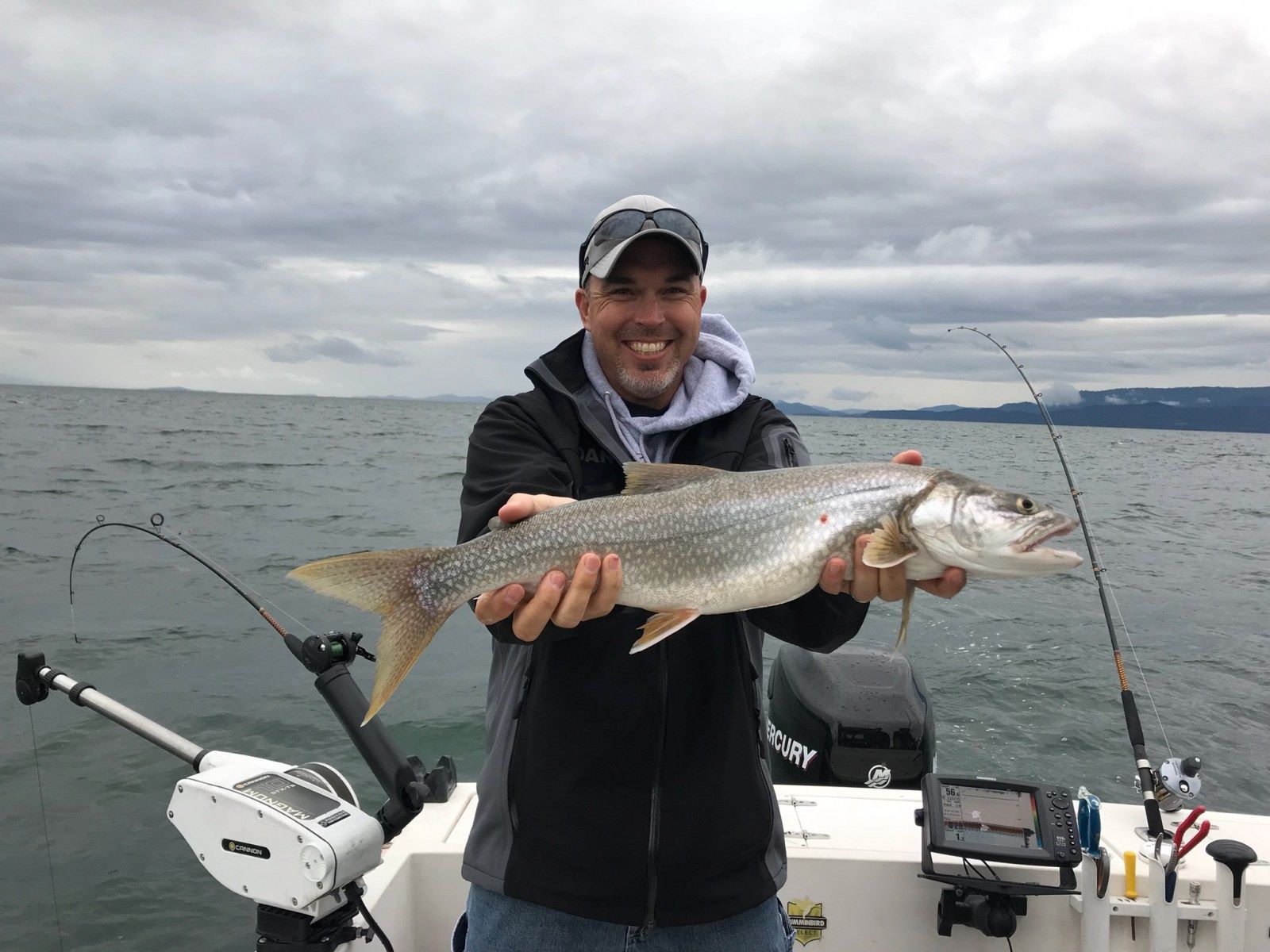 A man is holding a large fish on a boat.