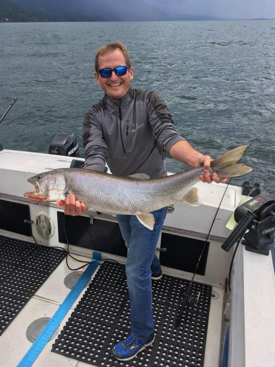 A man is holding a large fish on a boat.