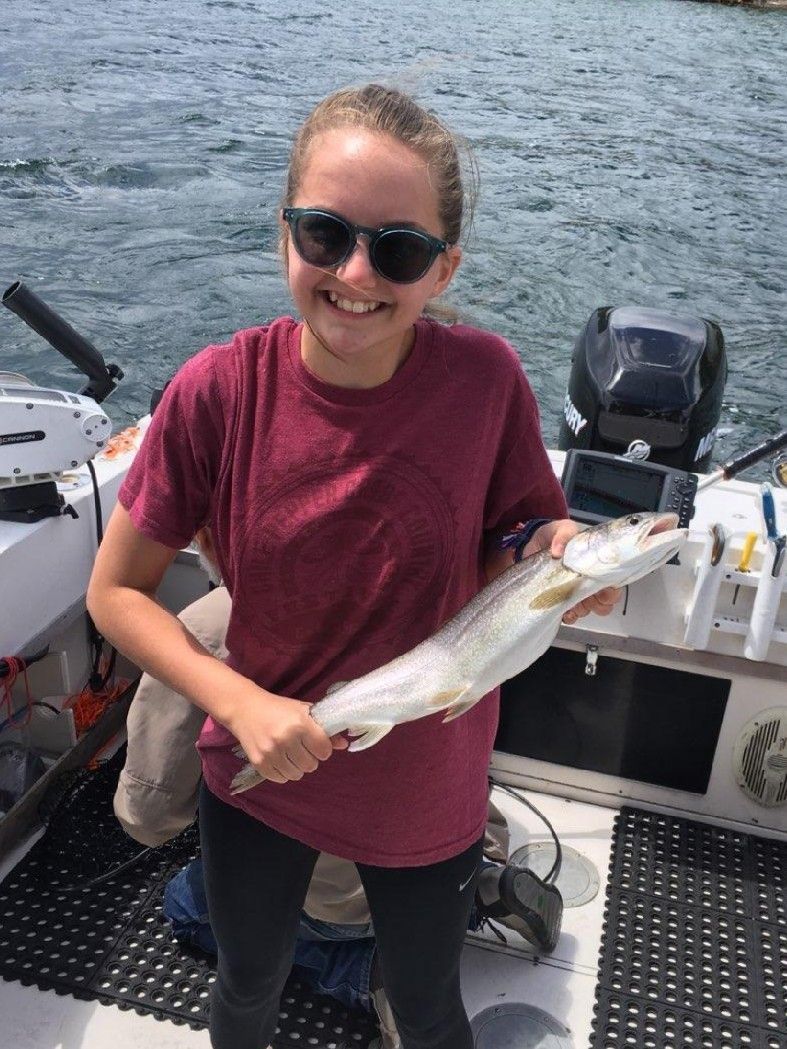 A young girl is holding a fish on a boat.