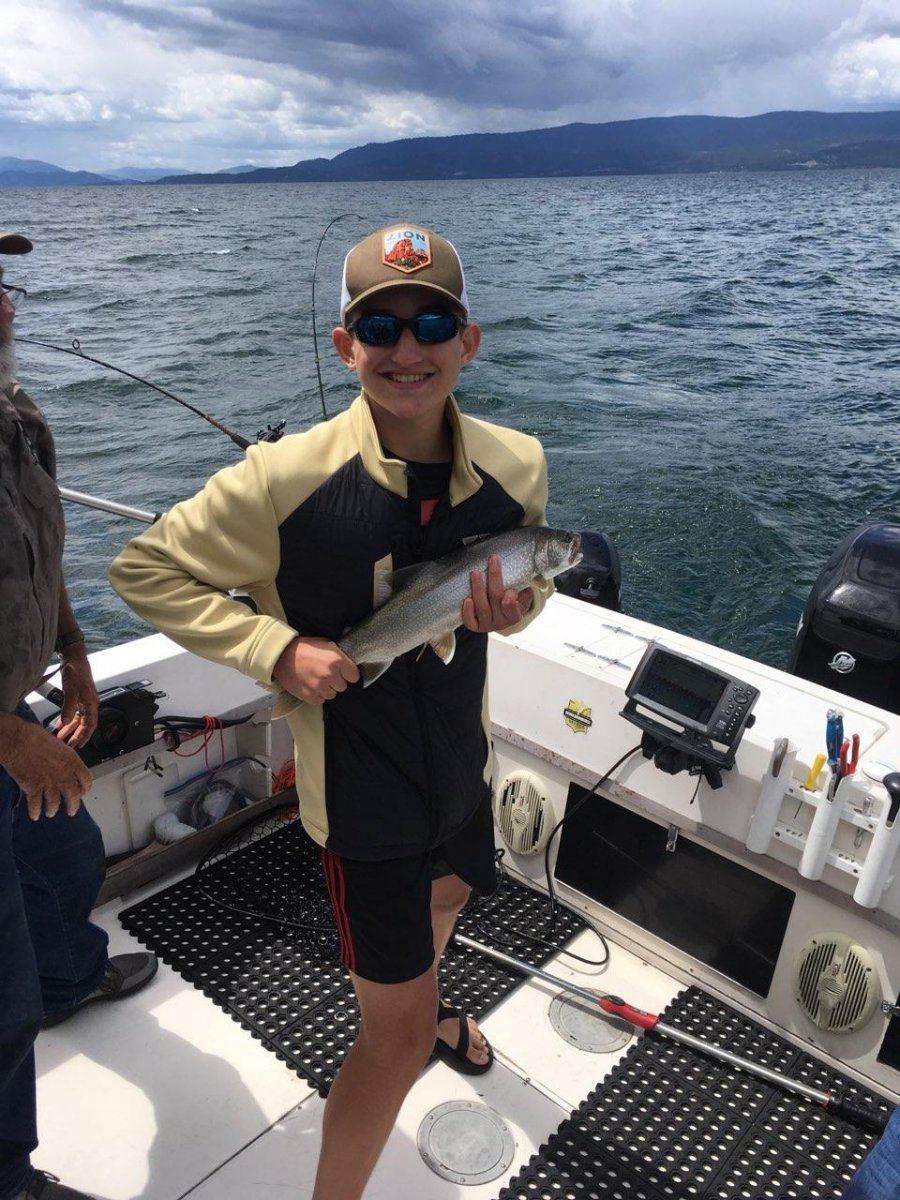 A young boy is holding a fish on a boat.