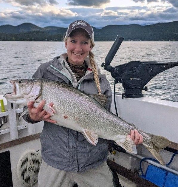 A woman is holding a large fish on a boat.