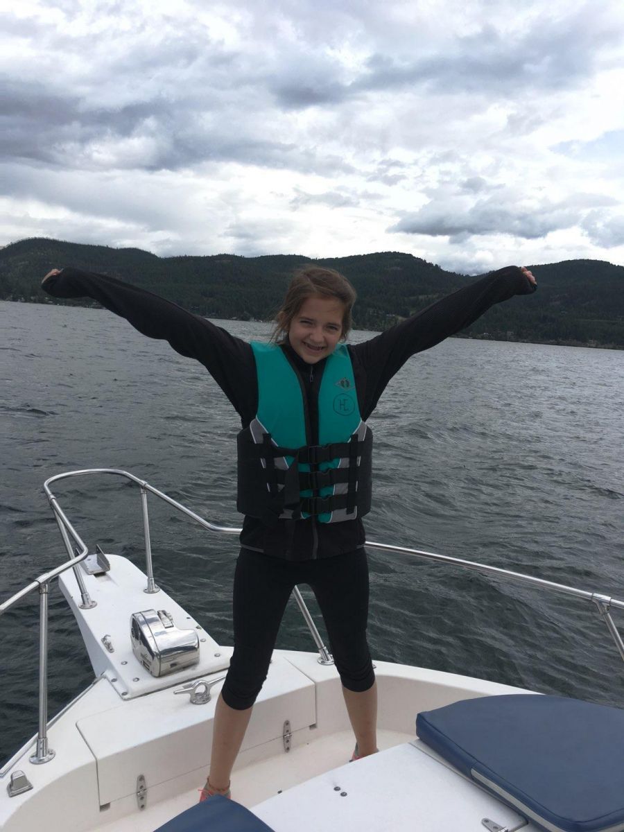 A girl wearing a life jacket is standing on a boat