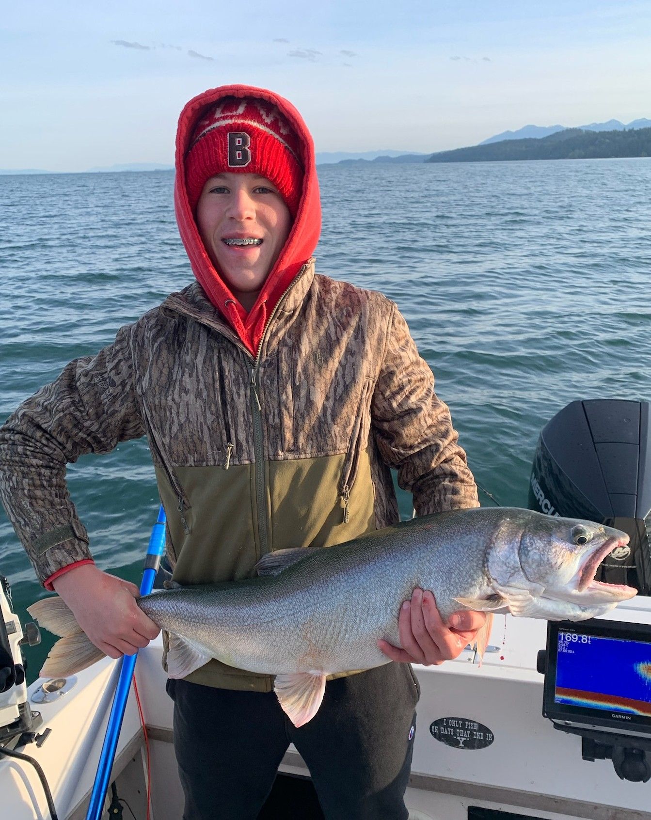 A young man is holding a large fish on a boat.