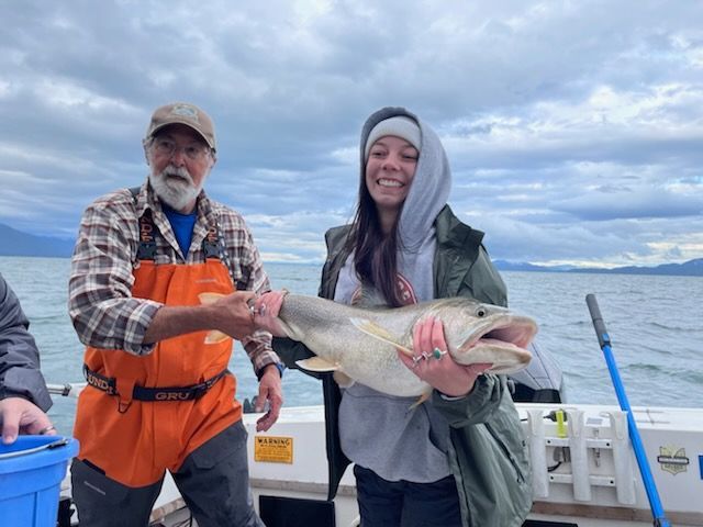 A man and a woman are holding a large fish on a boat.