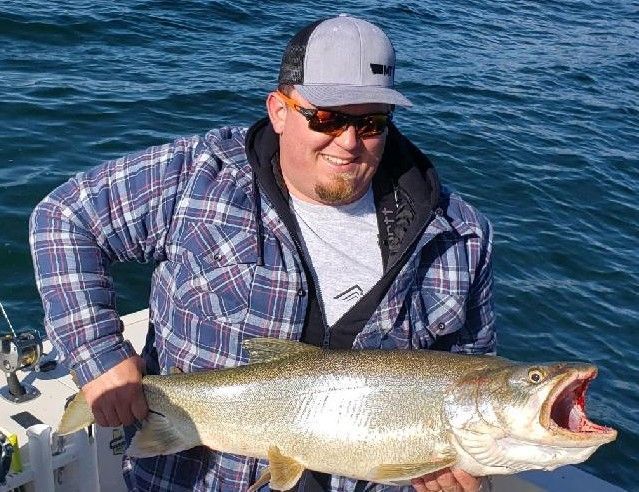 A man is holding a large fish on a boat.