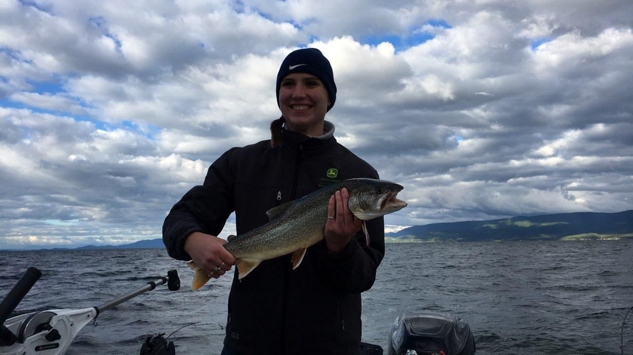 A man is holding a large fish in front of a body of water.