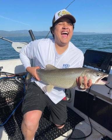 A man is holding a large fish on a boat.