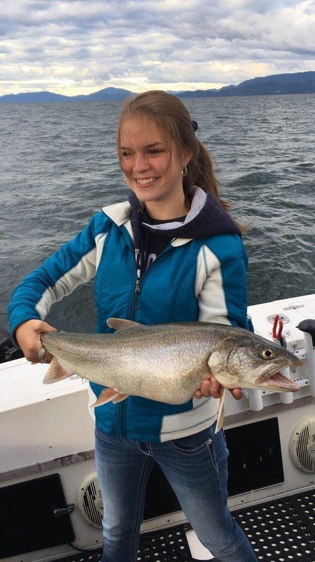 A young woman is holding a large fish on a boat.