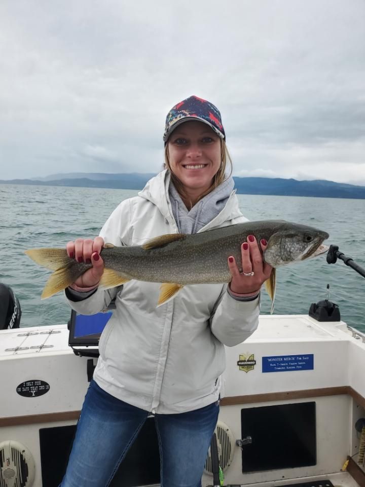 A woman is holding a fish on a boat in the water.