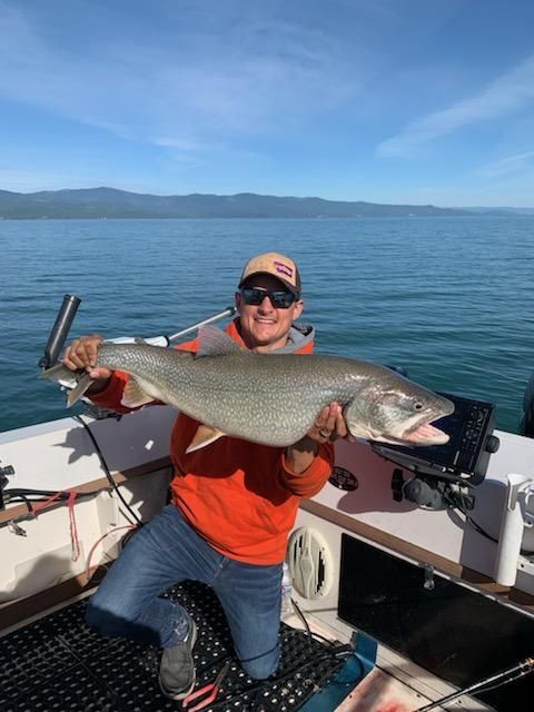 A man is kneeling on a boat holding a large fish.