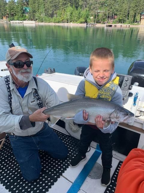 A man and a boy on a boat holding a fish