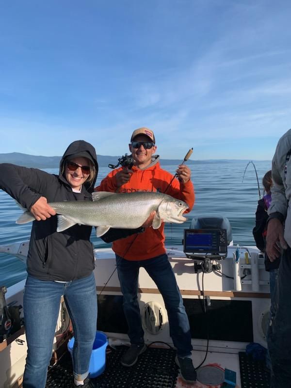 A man and a woman are holding a large fish on a boat.