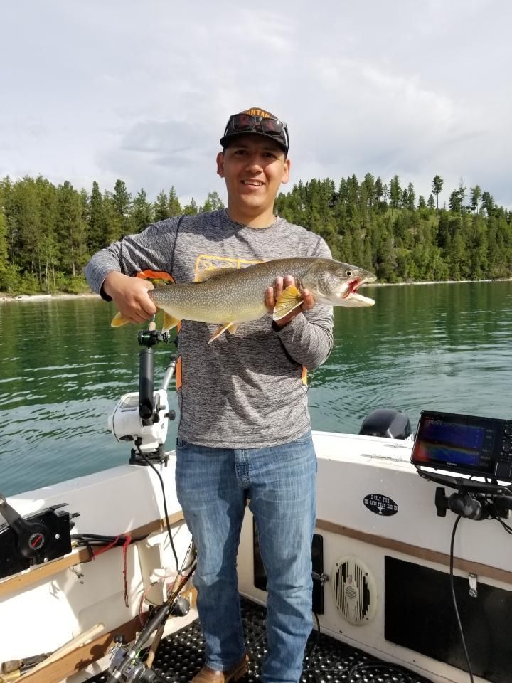 A man is standing on a boat holding a large fish.