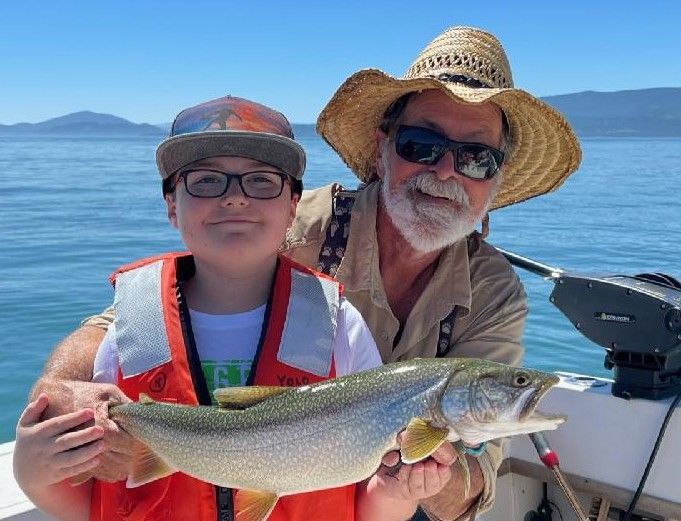 A man and a boy are holding a fish on a boat.