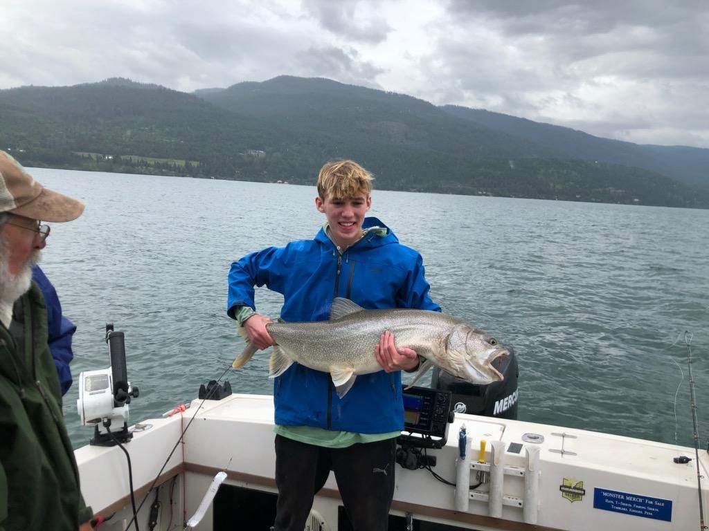 A young boy is holding a large fish on a boat.