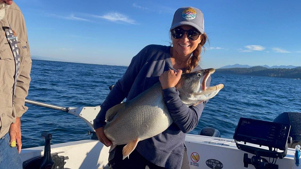 A woman is holding a large fish on a boat.