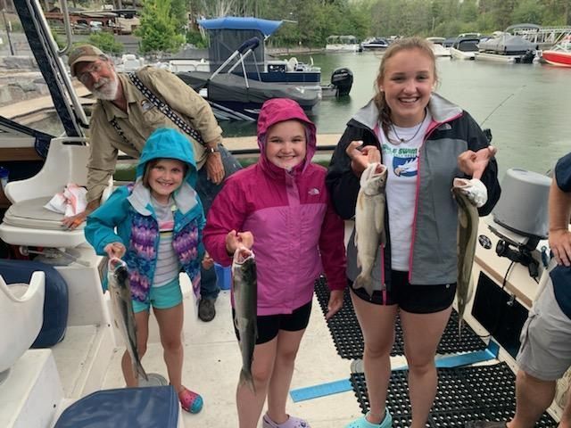 A group of people standing on a boat holding fish
