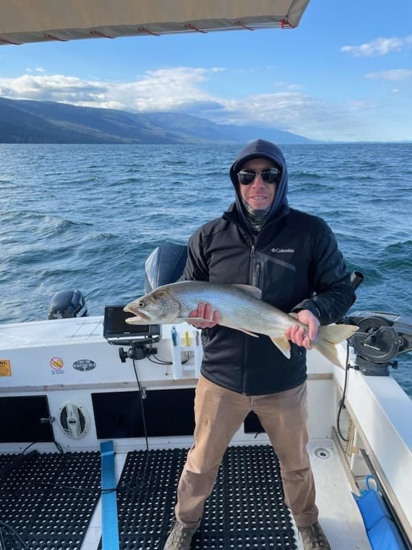 A man is standing on a boat holding a large fish.