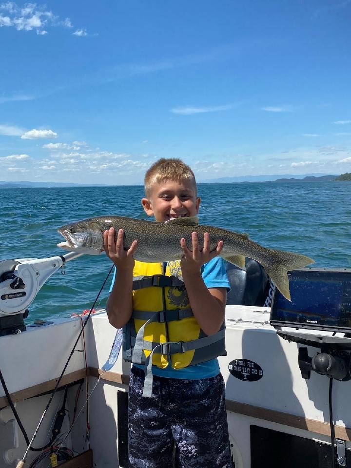 A young boy is holding a large fish on a boat.