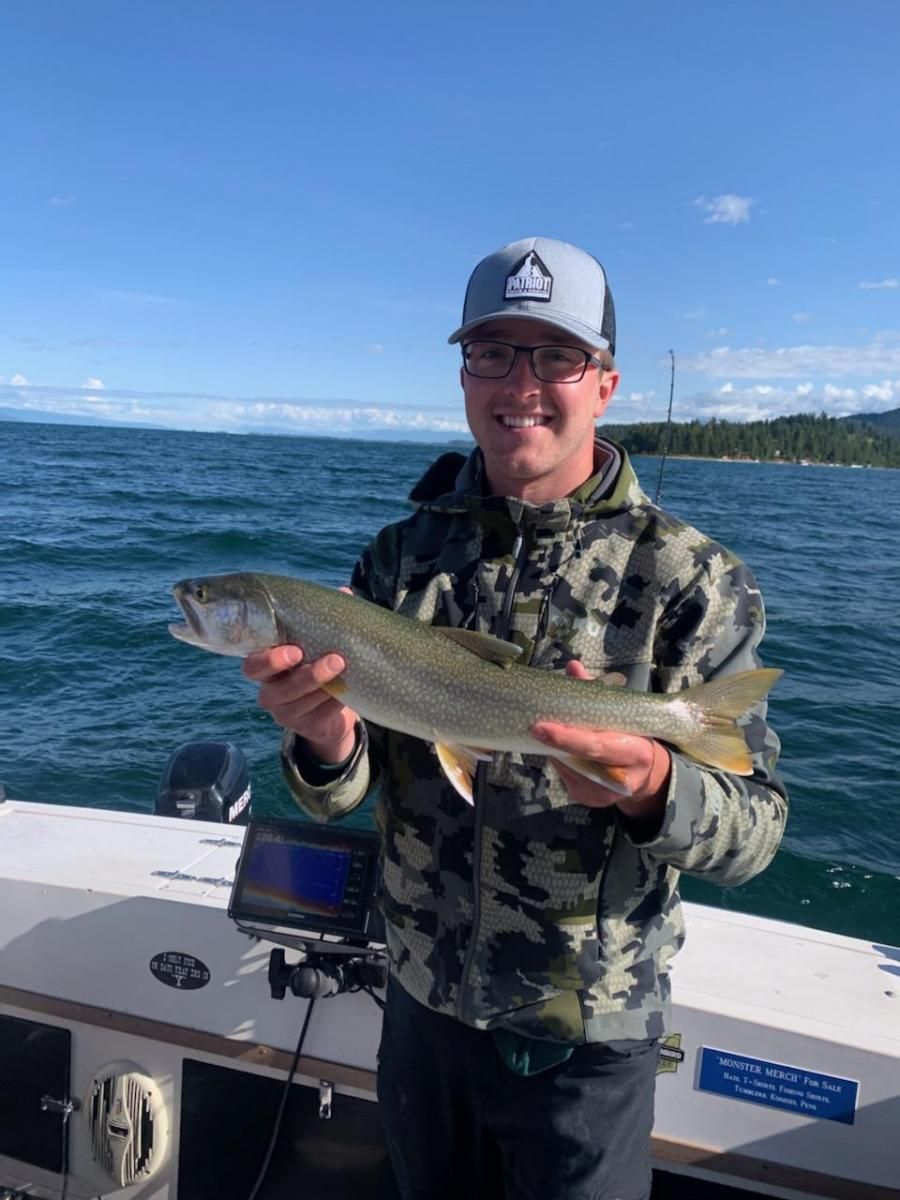 A man is holding a fish on a boat in the water.