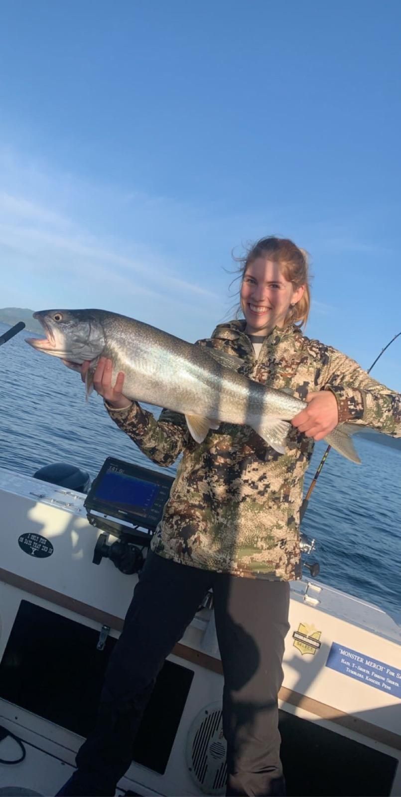 A woman is holding a large fish on a boat.