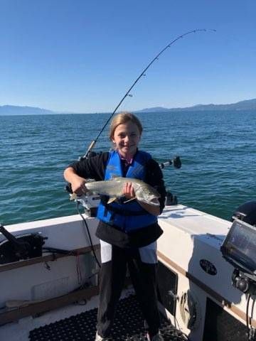 A young girl is holding a fish on a boat.