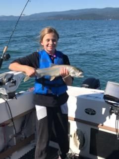 A young girl is holding a fish on a boat.